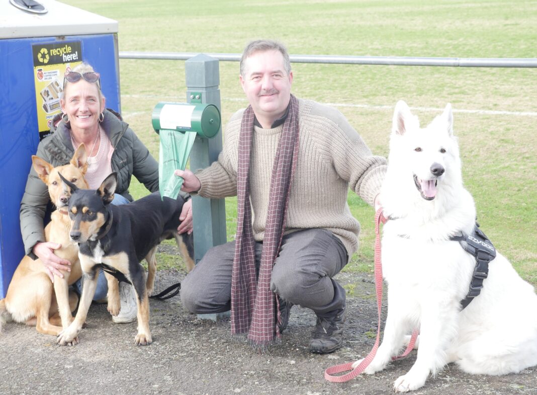 Dog bag dispensers Winchelsea community member Ange Parish with kelpies Louie and Zeek and Cr Adrian Schonfelder with white Swiss shepherd Whistler. scaled